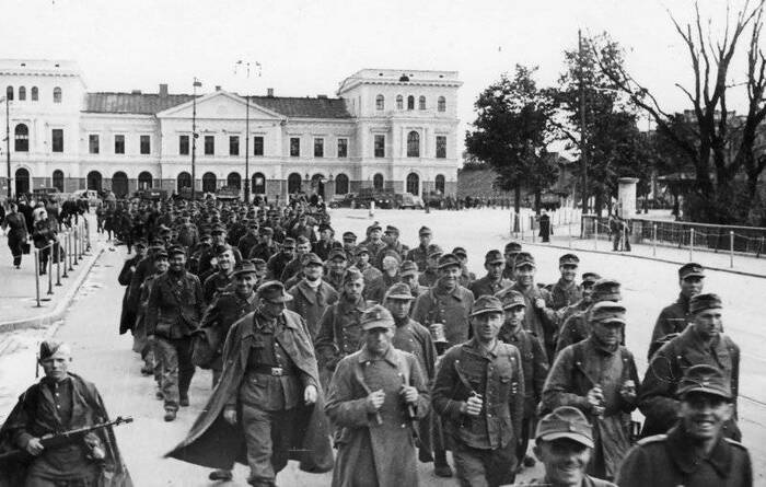 Колонна немецких военнопленных проходит мимо железнодорожного вокзала Риги