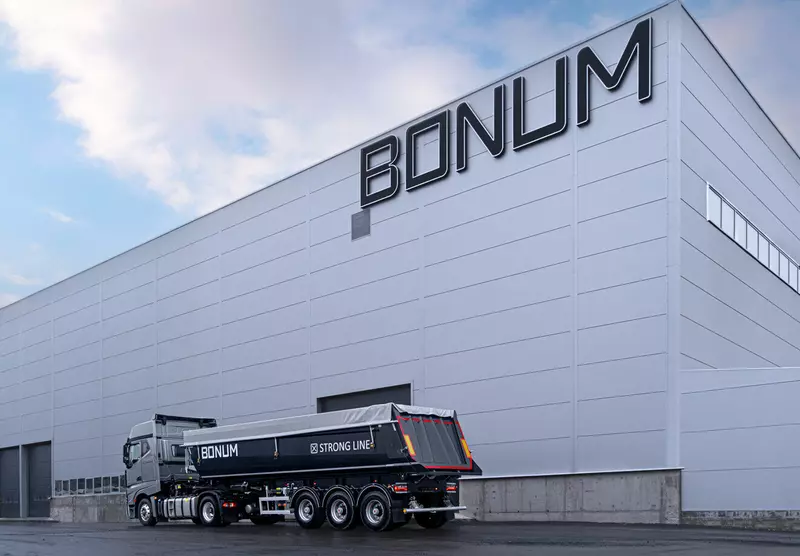 Полуприцеп-самосвал на фоне завода